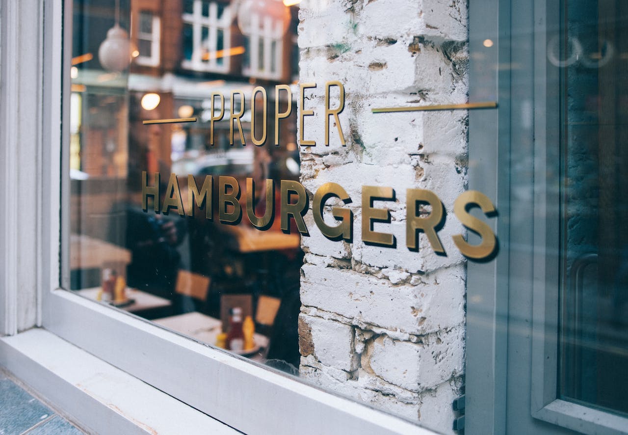 gold vinyl lettering on restaurant window that says proper hamburgers